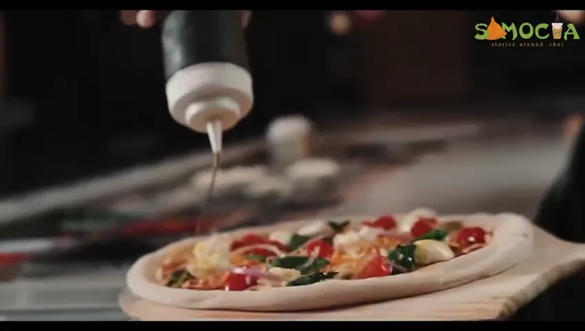 Pizza being finished with fresh toppings in a Samocha kitchen
