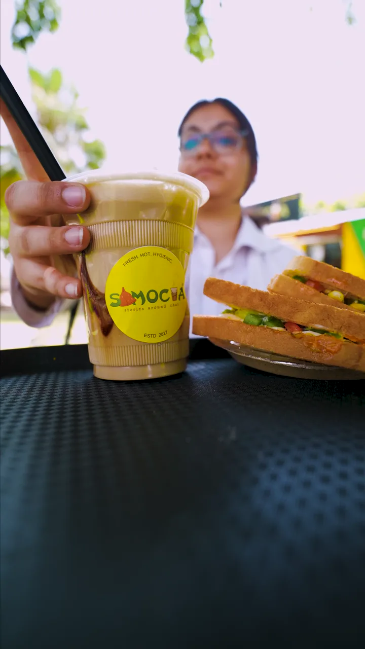 Chai and a sandwich being shared at an outdoor Samocha table